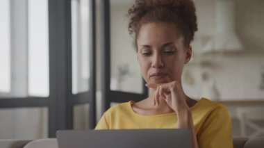 Düşünceli bir Afro-Amerikalı kadının laptopunu karıştırırken, 90 fps yavaş çekimde kapalı mekanda neşeli bir ruh hali içinde.