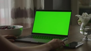 Yeşil ekranlı dizüstü bilgisayar. Tanınmayan bir kadının etrafında dönüp krom tuşlu el kamerasıyla bilgisayar izlerken 90 fps yavaş çekim.