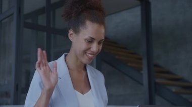 İş kadını görüntülü konuşma, video konferansındaki kadın. Afrikalı Amerikalı kadın yetişkin selamlama jesti bilgisayarını yavaş çekimde kapalı alanda kullanıyor.