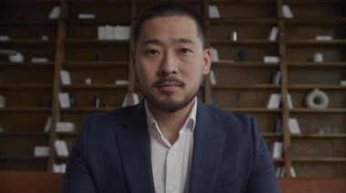 POV İşadamı Portresi. Takım Elbiseli Asyalı Adam. Girişimcinin başını çevirip kameraya baktığı düşük açı. Yavaş çekimde sakin ve kendinden emin.