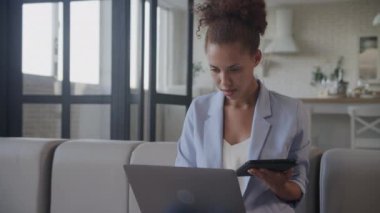 İş kadını tablet kullanıyor, kadın dizüstü bilgisayarda çalışıyor. Yetişkin Afro-Amerikan ağır çekimde tablet bilgisayar ve dizüstü bilgisayar kullanarak işleri yönetiyor