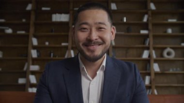 POV İşadamı Portresi. Asyalı Adam Yakından Gülümse. Düşük açılı çalışan başını çeviriyor ve kameraya bakıyor sakin ve kendinden emin bir şekilde ağır çekimde.