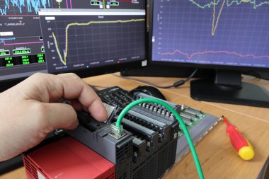 PLC 'yi yeniden başlatan elin yakın çekimi. Kablo bağlantısı detayı. Endüstriyel kontrol sisteminin test ve programlanması. Programlanabilir Mantık Denetleyici.