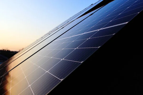 Evin çatısı fotovoltaik panellerle kaplı. Gün batımı. Yeşil enerji. Evin çatısında fotovoltaik elektrik santrali var..