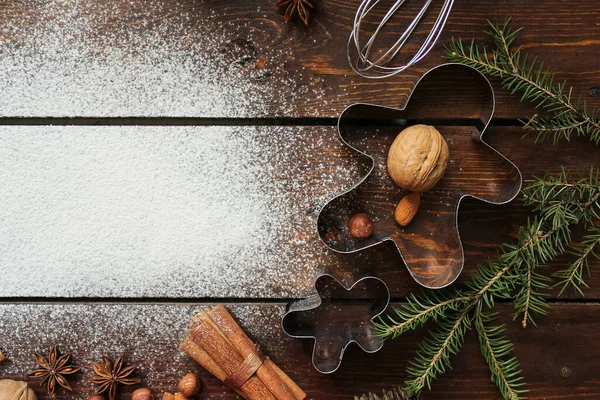 Noel kurabiyeleri, yıldız anason, tarçın, fındık, ladin dalları ahşap bir arka planda uzanır. Üzerinde un serpiştirilmiş metnin yeri vardır.