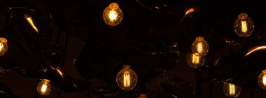 Siyah arka plan ve sıcak elektrik lambaları. Yatay Pankart