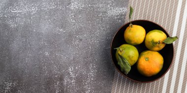 Siyah arka planda yaprakları olan mandalinalar. Üst manzara, düz uzanma