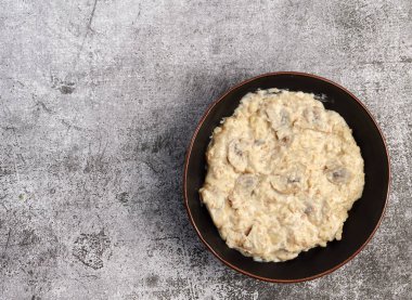 Siyah arka planda bir kasede lezzetli mantarlı yulaf ezmesi. Üst manzara, düz uzanma