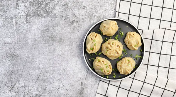 Manti - asian steam meat dumplings on a round plate on a dark grey background. Top view, flat lay