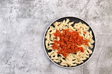 Koyu gri arka planda yuvarlak tabakta geleneksel makarna bolonez. Üst manzara, düz uzanma