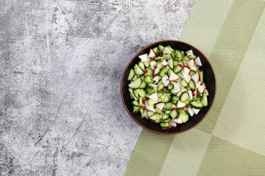 Koyu gri arka planda salatalık ve turp salatası. Üst manzara, düz uzanma