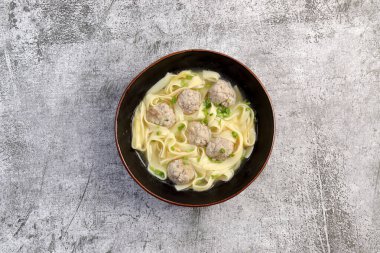 Koyu gri arka planda bir kasede köfte çorbası. Üst manzara, düz uzanma