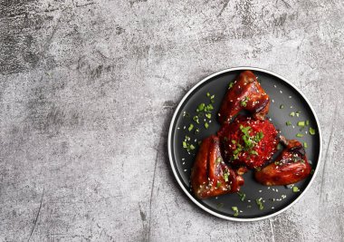 Koyu gri arka planda yuvarlak tabakta pancar pilavlı kızarmış tavuk kanadı. Üst manzara, düz uzanma