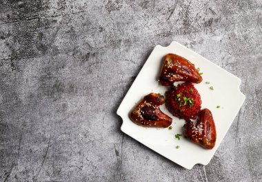 Kare tabakta koyu gri arka planda pancar risotto ile kızarmış tavuk kanadı. Üst manzara, düz uzanma