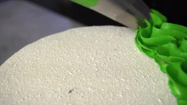 Yeşil krema pastanın üstüne pasta poşeti kullanılarak uygulanır. Yakın plan.
