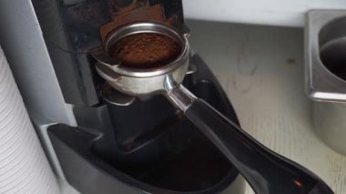 Kahve makinesinin tutacağı aromatik öğütülmüş kahveyle dolu. Kahveci öfkeyle bastırıyor.