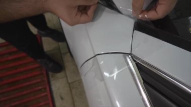 Keskin bir bıçakla, kaputtaki anti-yerçekimi filmini kes. Üst manzara, sol. Arabanın tekerleğini görebiliyorsun. Yakın plan. Ayrıntı