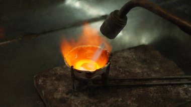 Gümüş ya da altın, mücevher yapmak için küf içindeki bir gaz ocağı tarafından eritilir..