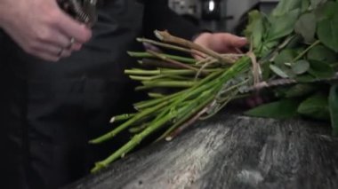 Çiçekçi bir budama makinesi alır ve buketteki çiçeklerin saplarını keser.