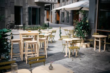 Güneşli bir günde, açık hava restoranındaki tahta bir masada çiçekler ve tabak.