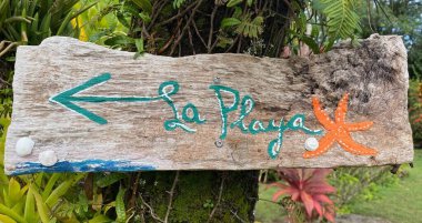Tahta, elle boyanmış ispanyolca yazılmış plaja giden yolu gösteren tabela..
