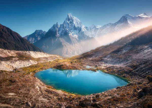 尼泊尔雪山 山顶明亮 湖面小 日出时有蓝色的水 美丽的风景 雪地高耸的岩石 金色的阳光 黎明时分的山丘 喜马拉雅山 — 图库照片