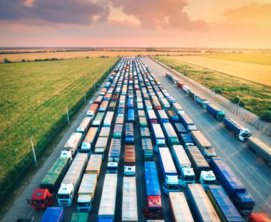 Yazın gündoğumunda terminaldeki renkli kamyonların hava görüntüsü. Lojistik merkezin en üst görüntüsü. Ağır endüstri. Ulaşım. Kargo nakliyesi, nakliye. Uluslararası taşımacılık. Arabaların üstünden görünüm