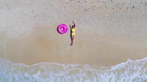 Veduta aerea di giovane donna con anello di nuoto rosa sulla spiaggia di sabbia — Video Stock