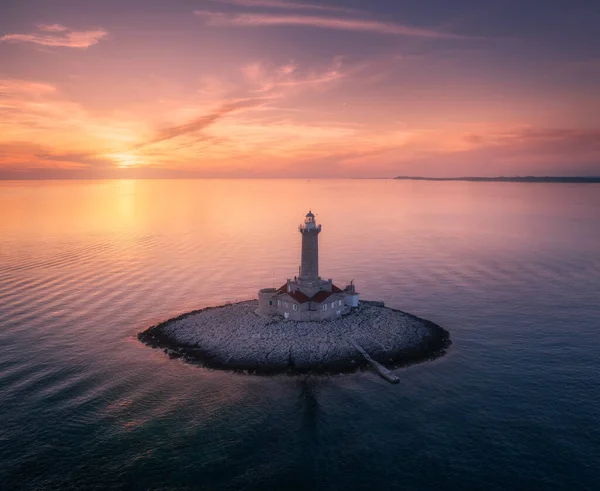 Faro su piccola isola nel mare al tramonto colorato in estate — Foto Stock