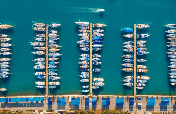 Aerial view of boats and luxure yachts in dock at sunset in summer in Pula, Croatia. Colorful landscape with sailboats and motorboats in sea bay, jatty, clear blue sea. Top view of harbor. Travel