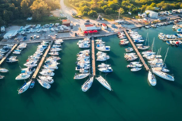 Aerial view of boats and luxure yachts in dock at sunset in summer in Pula, Croatia. Colorful landscape with sailboats and motorboats in sea bay, jatty, clear blue sea. Top view of harbor. Travel