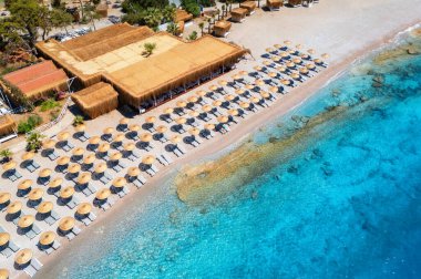 Şemsiyeli kumlu kumsal manzarası, yazın günbatımında yeşil ağaçlar. Oludeniz, Türkiye 'deki mavi göl. Deniz koylu tropikal manzara, şeffaf mavi su. İHA 'nın üst görüntüsü. Doğa