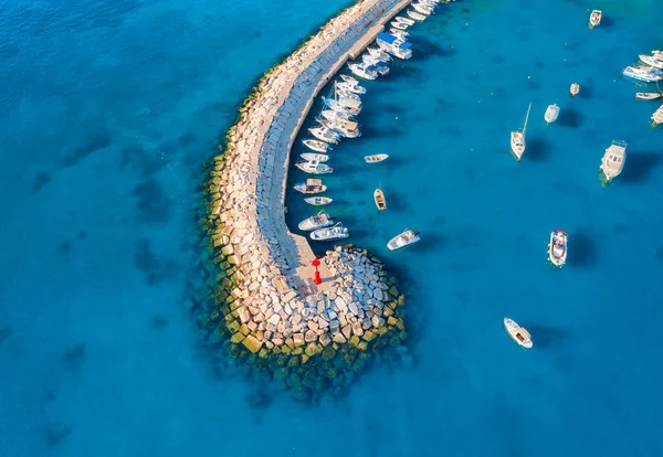 Aerial view of boats and luxure yachts in dock, breakwater and blue sea at sunset in summer in Fazana, Croatia. Colorful landscape with sailboats and motorboats, jatty, clear water. Top view of harbor
