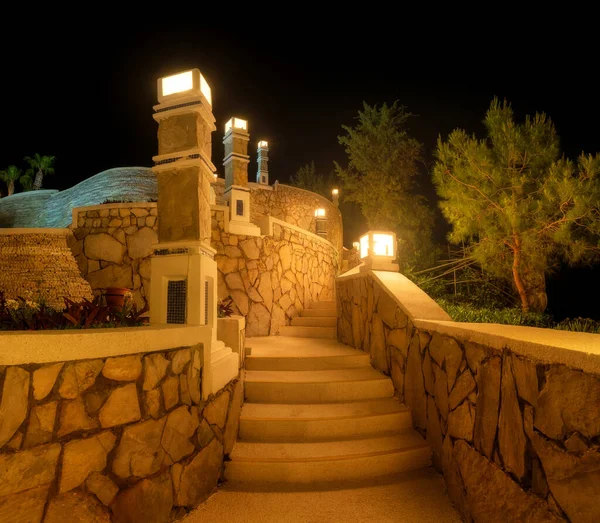Beautiful stairs with street light at night in summer. Colorful landscape with stones steps, illumination, green trees. Beautiful architecture in Oludeniz, Turkey. City lights. Lamps on the wall