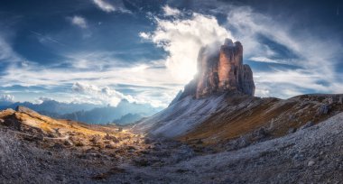 Mountain pass and blue sky with clouds at sunset in autumn. Beautiful panoramic landscape with rocks, alp mountains, stones, path, house, grass on hills. Tre Cime, Dolomites, Italy. Colorful scenery