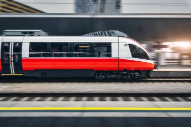 Viyana 'daki modern tren istasyonunda hızlı tren hareket ediyor. Hareket bulanıklığı olan hızlı kırmızı şehirlerarası yolcu treni. Demiryolu platformu. Avrupa 'da demiryolu. Ticari ulaşım. Aktarım