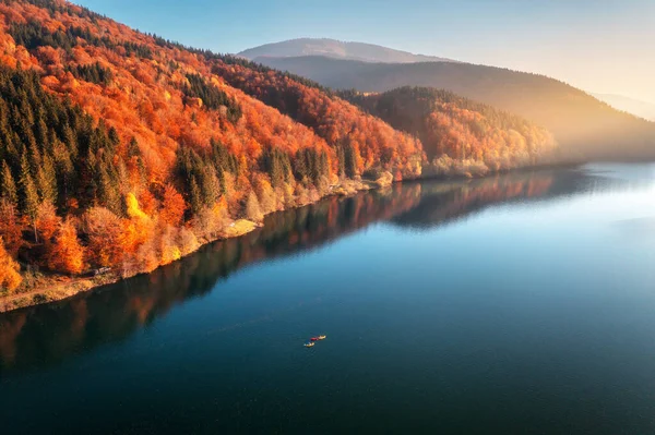 秋天的落日 人们乘坐着五彩缤纷的小船在蓝色的湖面上漂浮 群山丛生 森林一片鲜红 秋天乌克兰喀尔巴阡山脉的河流 独木舟的头像 — 图库照片