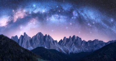 Dolomitler, İtalya 'da yazın yıldızlı bir gecede Samanyolu' nu yıktı. Yıldızlı mor gökyüzü ve yüksek dağların üzerinde parlak Samanyolu kemeri. Uzay arkaplanı. Doğa