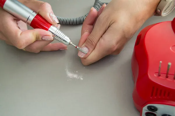 Jel cilasını manikür değirmen makinesinin yardımıyla kaldırma süreci. Evde manikür.