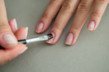 Kadın tırnaklarına jöle sürmeden önce fırça tabanı uygulamak. Evde manikür.