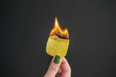 Kızın elinde yanan cipsler var. Alevler bir kadının elinde. Zararlı ve ekstra kalori yakmak