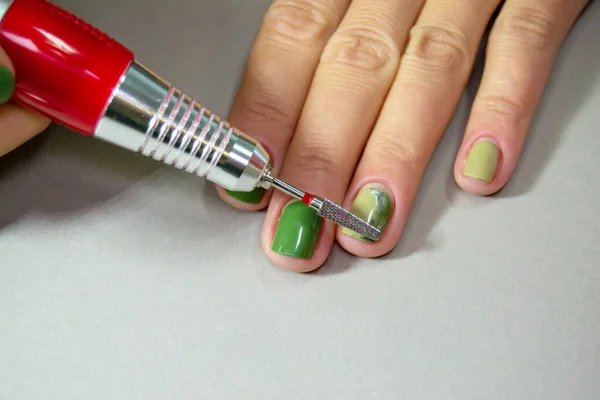 用修指甲机切割凝胶指甲油的过程 去除妇女指甲上的清漆 机器修指甲 绿色的指甲 水平图像 — 图库照片