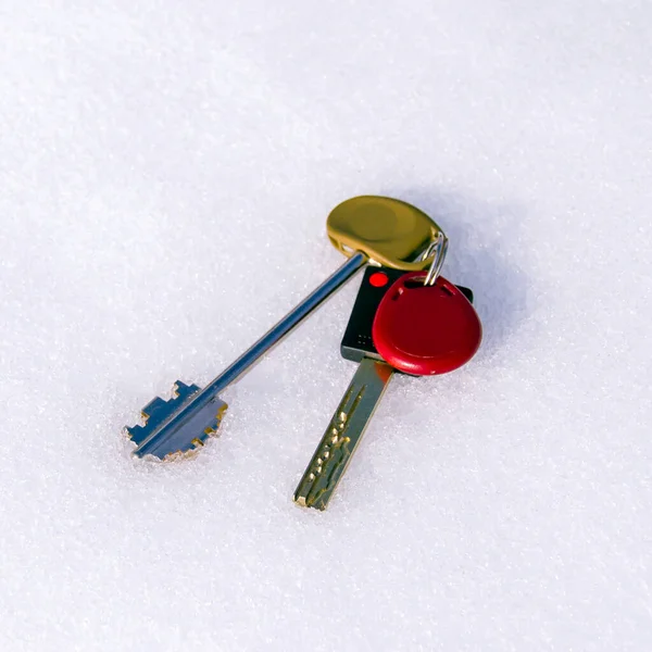 Karda anahtarlar. Donmuş inşaat. Ev satışları için soğuk sezon. Kilitlemek için anahtarlar beyaz karda yatıyor. Kare resim
