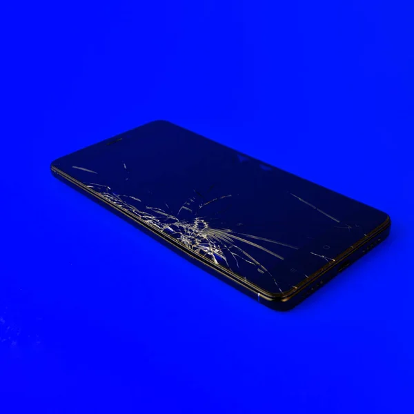 Мобильный Телефон Сломанным Экраном Лежит Синем Фоне Сломанный Смартфон Электронный — стоковое фото
