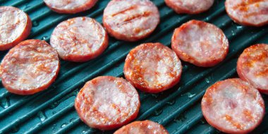 Izgara sosis dilimleri. Izgara tavasında sosisler. Piknik. Yağlı et. Yarı bitmiş ürünlerin hazırlanması. Siteye eklenmek için pankart.