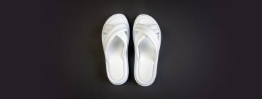 Siyah arka planda beyaz kadın terlikleri. Terlikler. Bölgeye yerleştirme pankartı. Metin koşu alanı için yer. Yatay resim