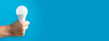 El ele tutuşan lamba. Bir fikrim var. Yeni fikir ya da ilham konsepti. Başlangıç konsepti. mavi arka plan. Bölgeye yerleştirme pankartı. Metin koşu alanı için yer. Yatay resim.