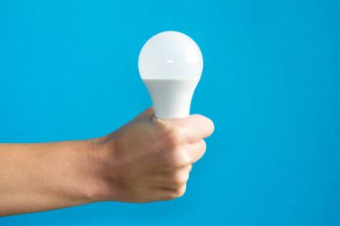 El ele tutuşan lamba. Bir fikrim var. Yeni fikir ya da ilham konsepti. Başlangıç konsepti. mavi arka plan. Yatay resim.