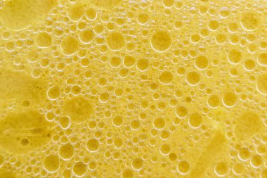 Suyun yüzeyinde hava kabarcıkları. Su emülsiyonunda yağlı halkalar. Kabarcıklı sarı sıvı. Yatay resim.