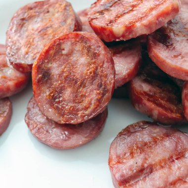 Beyaz bir tabakta sosis dilimleri. Piknik. Yağlı et, yarı bitmiş ürünlerin hazırlanması. Kare resim.